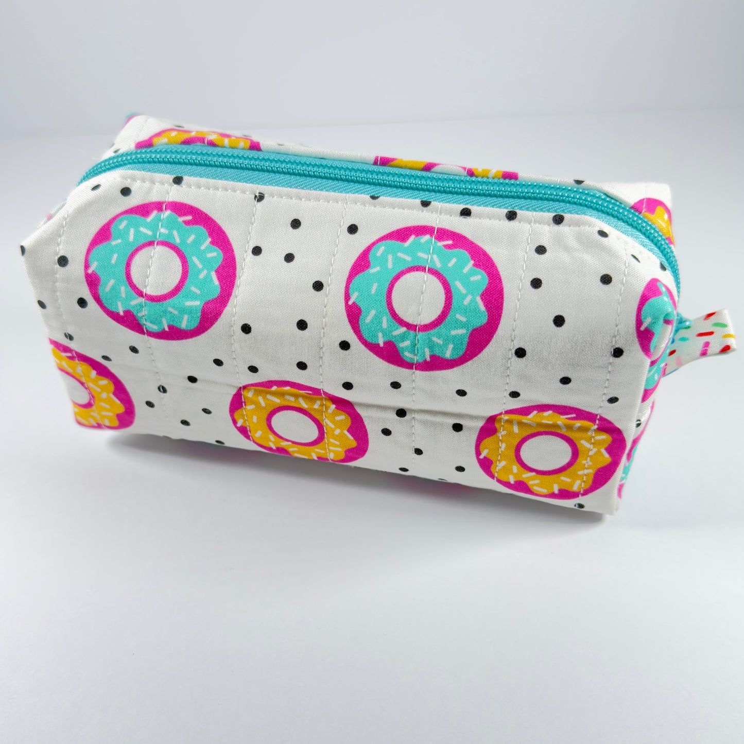 Pencil case with donut pattern and turquoise zipper on a light gray background